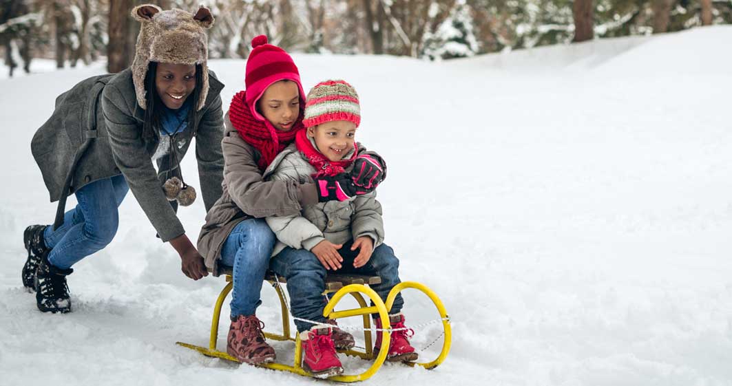 Three children sledding on a snowy hill.